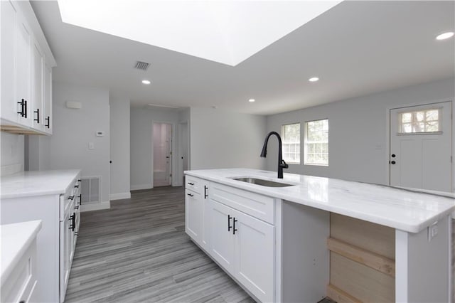 5023 Santos Dr W, Mobile, AL 36619 - kitchen with recessed lighting, white cabinetry, light wood-type flooring, a center island with sink, and light stone counters