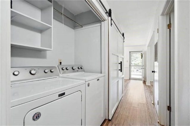 6050 Grelot Rd Unit 202, Mobile, AL 36609 - clothes washing area with light wood-style floors, laundry area, a barn door, and washer and dryer