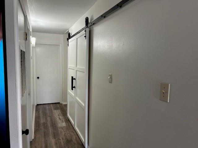 6050 Grelot Rd Unit 202, Mobile, AL 36609 - corridor featuring a barn door and dark wood-style floors