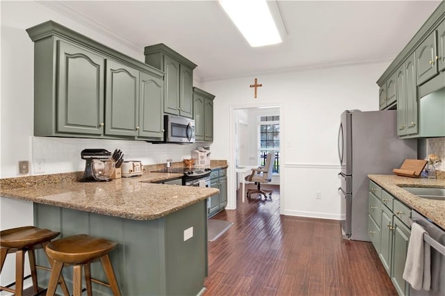 kitchen with dark hardwood / wood-style flooring, stainless steel appliances, green cabinetry, and backsplash