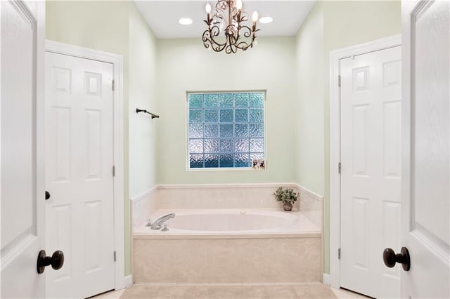 bathroom with tile patterned flooring, an inviting chandelier, and a tub