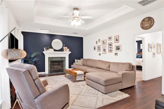 living room with hardwood / wood-style floors, crown molding, a high end fireplace, and a tray ceiling