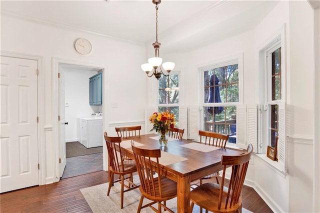 dining area with dark hardwood / wood-style flooring, independent washer and dryer, ornamental molding, and a chandelier