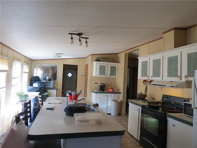 kitchen featuring black range with electric cooktop, a kitchen island, white cabinetry, ventilation hood, and dark countertops