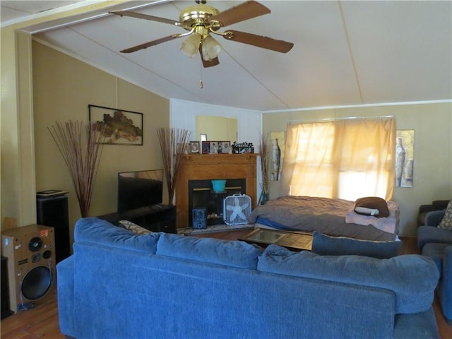 living room with a ceiling fan, vaulted ceiling, and wood finished floors