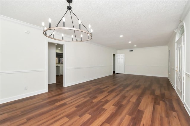 unfurnished room with an inviting chandelier, dark wood-type flooring, a textured ceiling, and ornamental molding