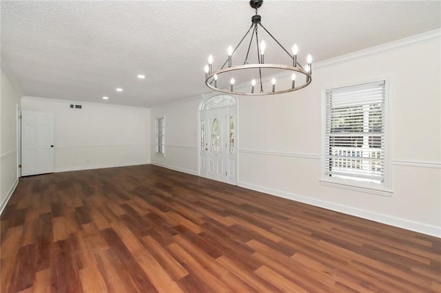 unfurnished dining area with a notable chandelier, dark hardwood / wood-style floors, ornamental molding, and a textured ceiling