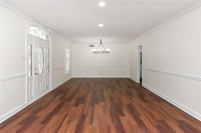 entrance foyer featuring ornamental molding, a textured ceiling, an inviting chandelier, and dark wood-type flooring