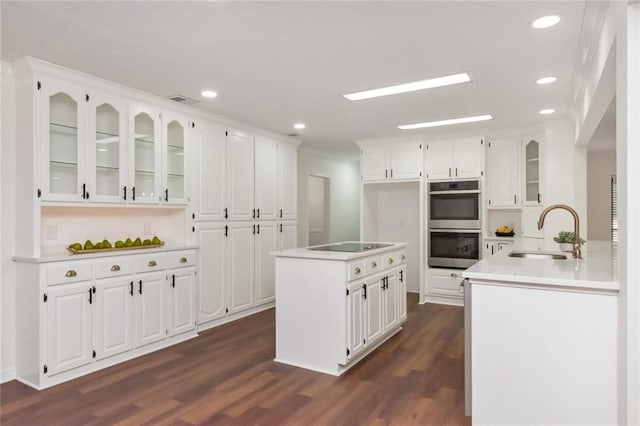 kitchen featuring sink, dark wood-type flooring, double oven, black electric stovetop, and white cabinets