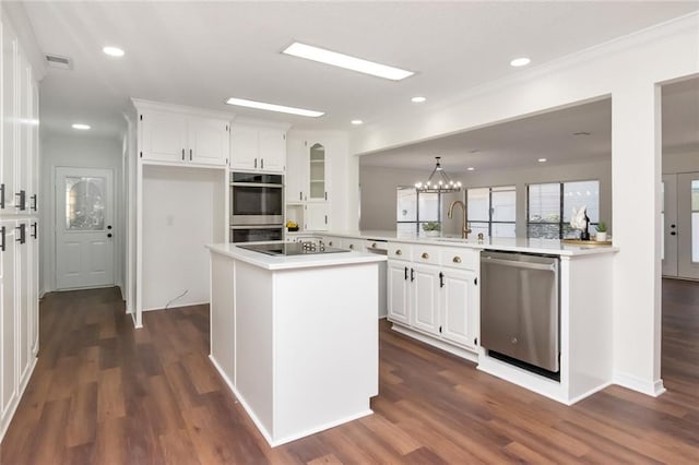 kitchen with kitchen peninsula, appliances with stainless steel finishes, white cabinets, and dark wood-type flooring