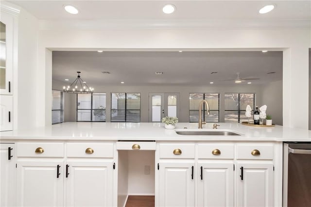 kitchen with ceiling fan with notable chandelier, sink, kitchen peninsula, stainless steel dishwasher, and white cabinetry