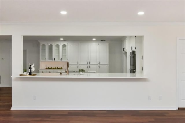 kitchen with white cabinets, dark hardwood / wood-style floors, kitchen peninsula, and ornamental molding