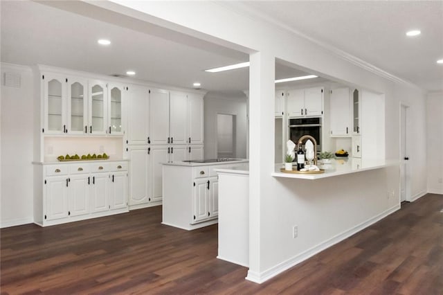 kitchen featuring dark hardwood / wood-style floors, white cabinetry, kitchen peninsula, and ornamental molding