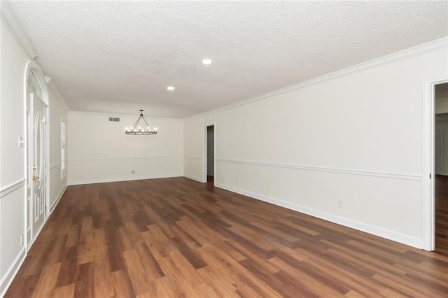 spare room with a textured ceiling, dark hardwood / wood-style floors, and a notable chandelier