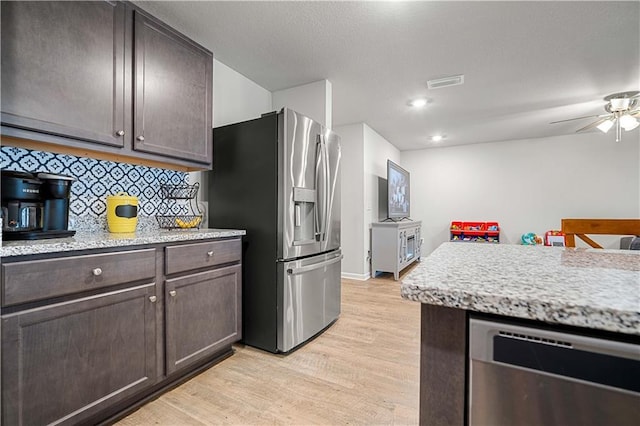 kitchen with dark brown cabinetry, backsplash, appliances with stainless steel finishes, and light hardwood / wood-style flooring