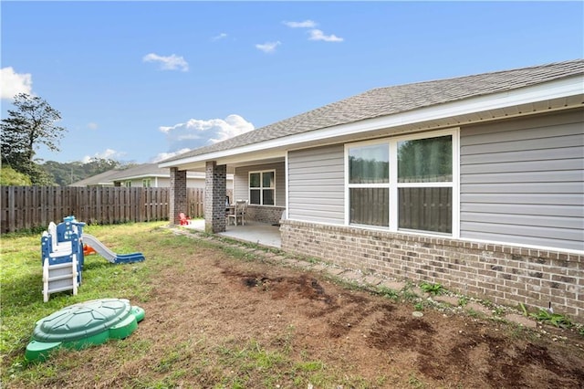 back of property featuring a lawn, a patio area, and a playground