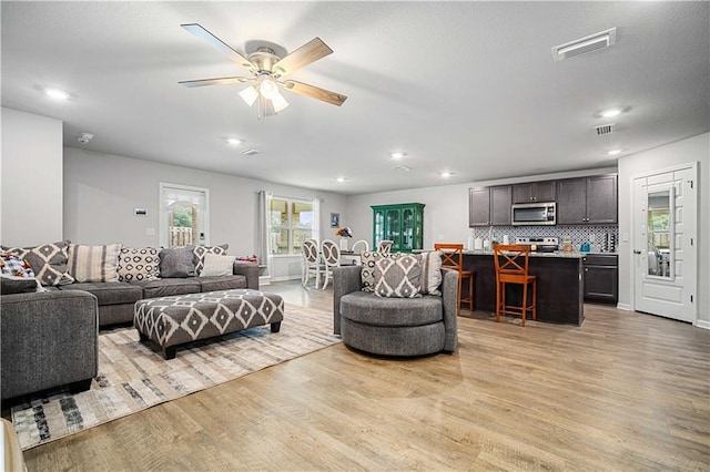 living room with ceiling fan and light hardwood / wood-style flooring