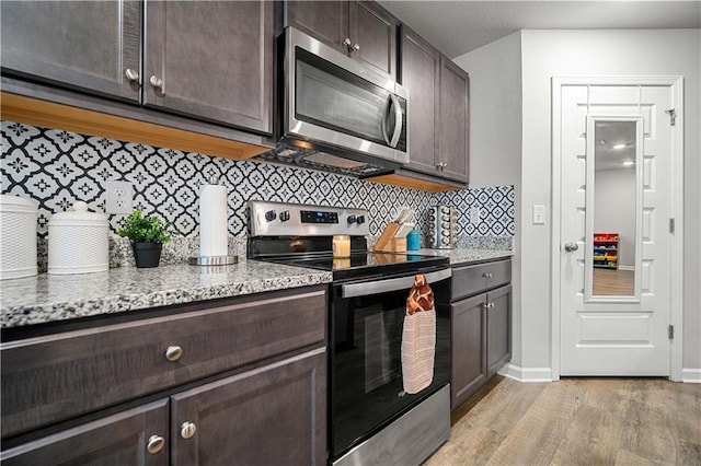 kitchen with light stone counters, light hardwood / wood-style floors, appliances with stainless steel finishes, and dark brown cabinets