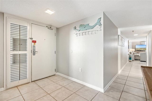 corridor with a textured ceiling and light tile floors