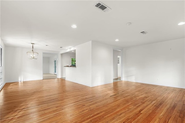 unfurnished room with an inviting chandelier and light hardwood / wood-style floors