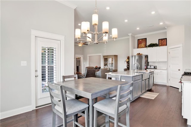 dining space with an inviting chandelier, dark hardwood / wood-style floors, sink, and crown molding