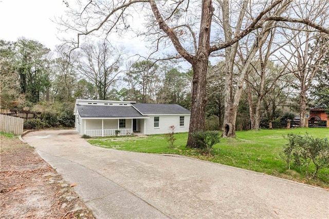 view of front of property featuring covered porch, a front lawn, and fence