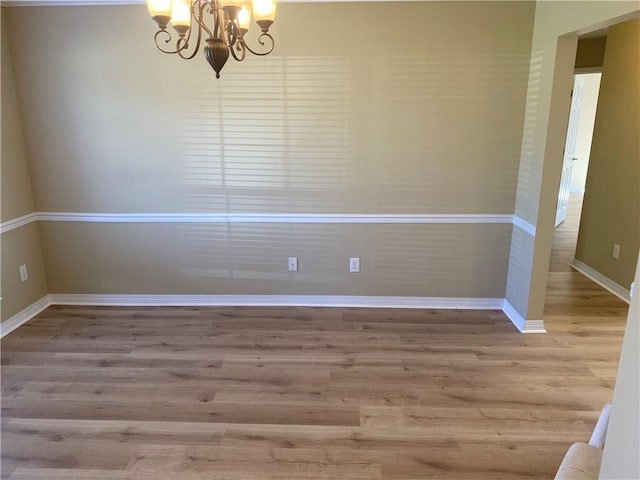 empty room featuring a chandelier and hardwood / wood-style floors