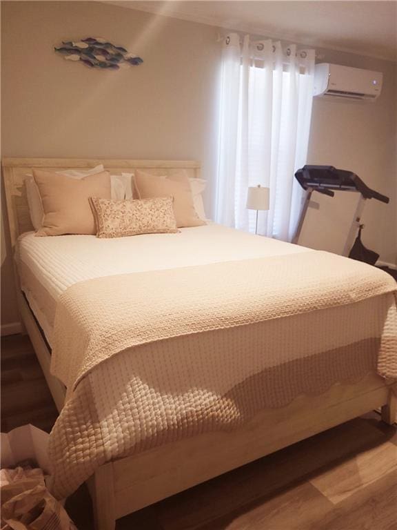 bedroom featuring a wall mounted air conditioner and hardwood / wood-style floors