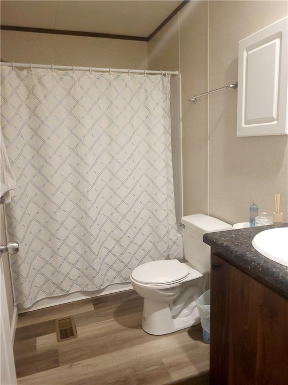 bathroom featuring vanity, hardwood / wood-style flooring, crown molding, and toilet