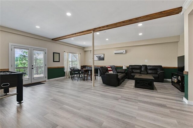 living room with beam ceiling, light hardwood / wood-style floors, french doors, and a wall mounted air conditioner