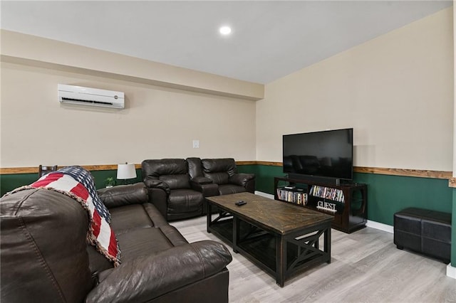 living room with a wall unit AC and light hardwood / wood-style floors