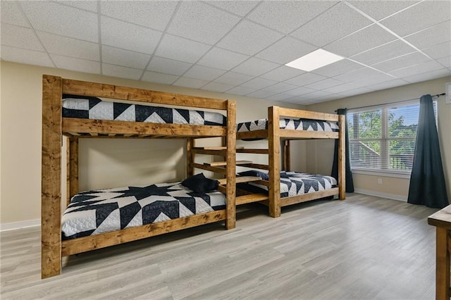 bedroom with a paneled ceiling and light hardwood / wood-style floors