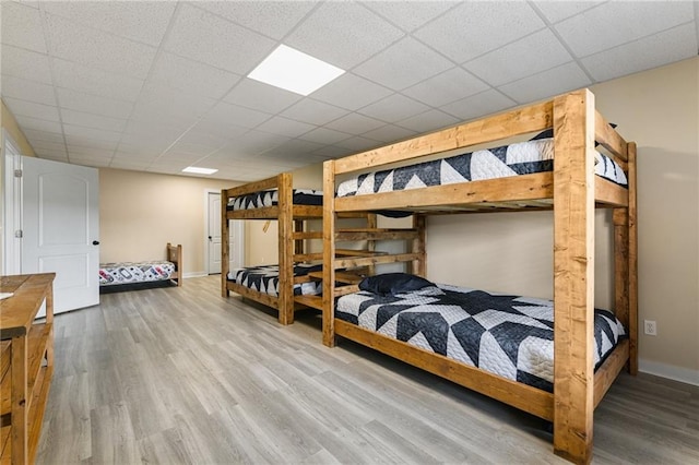 bedroom with a paneled ceiling and light wood-type flooring