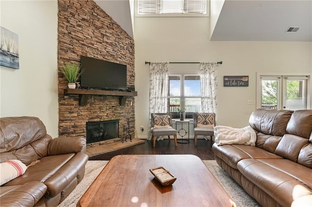 living room featuring dark hardwood / wood-style flooring, a fireplace, and a towering ceiling