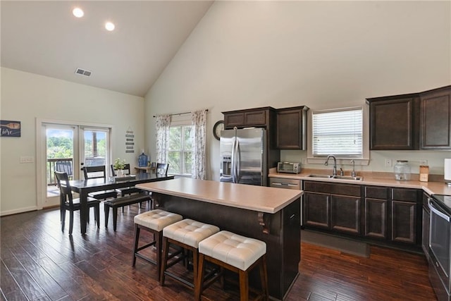 kitchen featuring stainless steel fridge, sink, a center island, dark wood-type flooring, and high vaulted ceiling