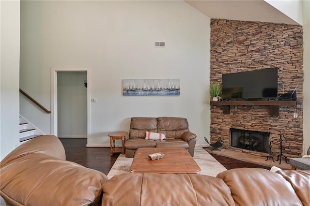 living room featuring a stone fireplace, dark wood-type flooring, and high vaulted ceiling