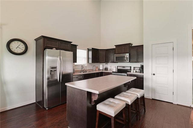 kitchen featuring a center island, a towering ceiling, dark hardwood / wood-style floors, and stainless steel appliances