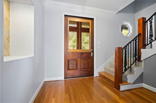 foyer entrance with hardwood / wood-style flooring and crown molding