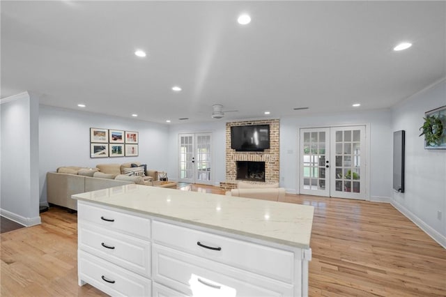 kitchen featuring french doors, white cabinetry, light hardwood / wood-style flooring, and light stone counters