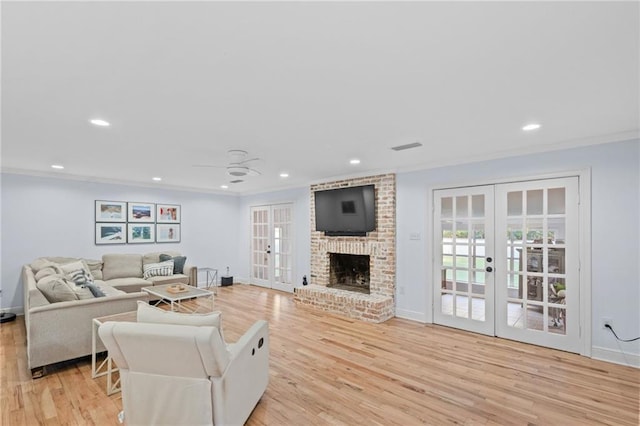 living room with ceiling fan, french doors, light hardwood / wood-style floors, a fireplace, and ornamental molding