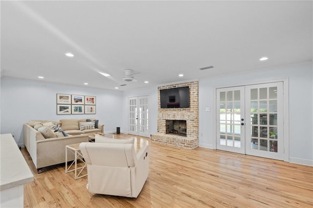 living room with a fireplace, french doors, and light hardwood / wood-style flooring