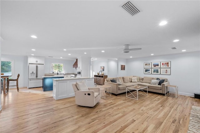 living room with sink, light hardwood / wood-style floors, a wealth of natural light, and ceiling fan