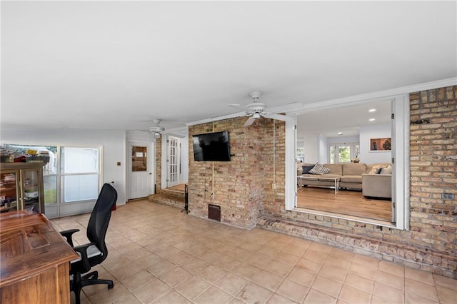 tiled office featuring a wealth of natural light, crown molding, ceiling fan, and brick wall