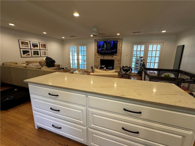 kitchen featuring light stone countertops, french doors, ceiling fan, and wood-type flooring