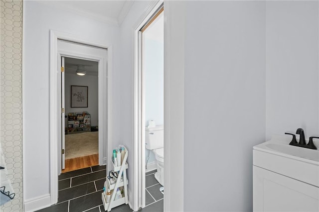 bathroom featuring toilet, vanity, wood-type flooring, and ornamental molding