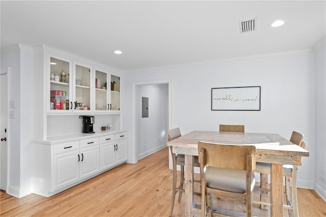 dining area with ornamental molding, electric panel, and light hardwood / wood-style flooring