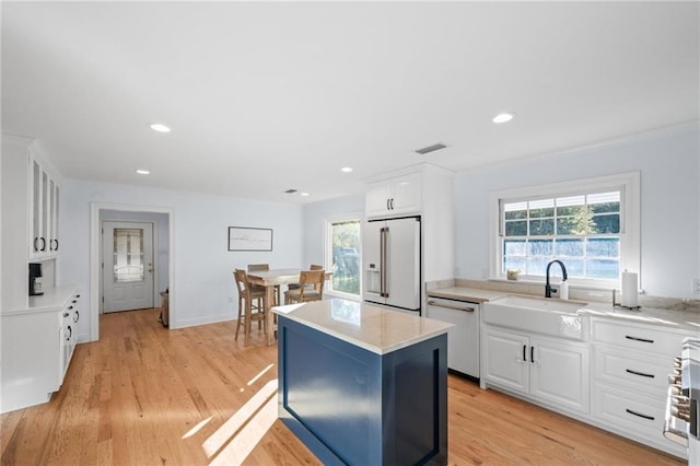 kitchen featuring white cabinets, a kitchen island, light wood-type flooring, and white appliances