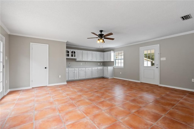 unfurnished living room with a textured ceiling, ceiling fan, ornamental molding, and light tile patterned flooring