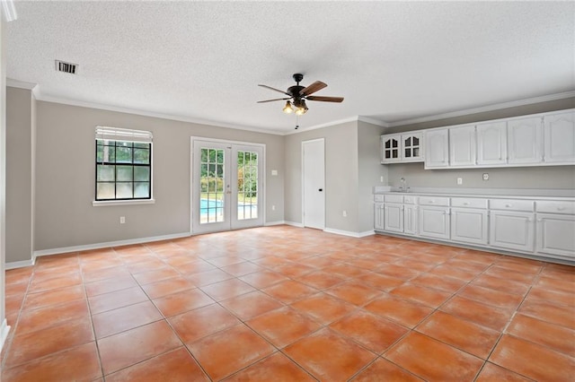 unfurnished living room with french doors, ornamental molding, a textured ceiling, ceiling fan, and light tile patterned floors