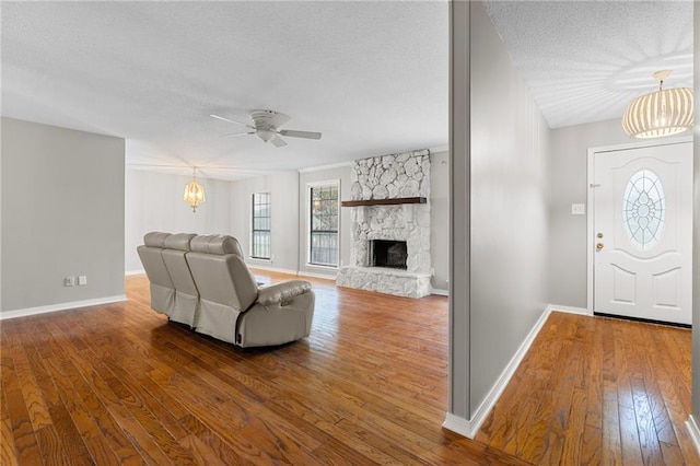 living room featuring a fireplace, hardwood / wood-style floors, ceiling fan with notable chandelier, and a textured ceiling